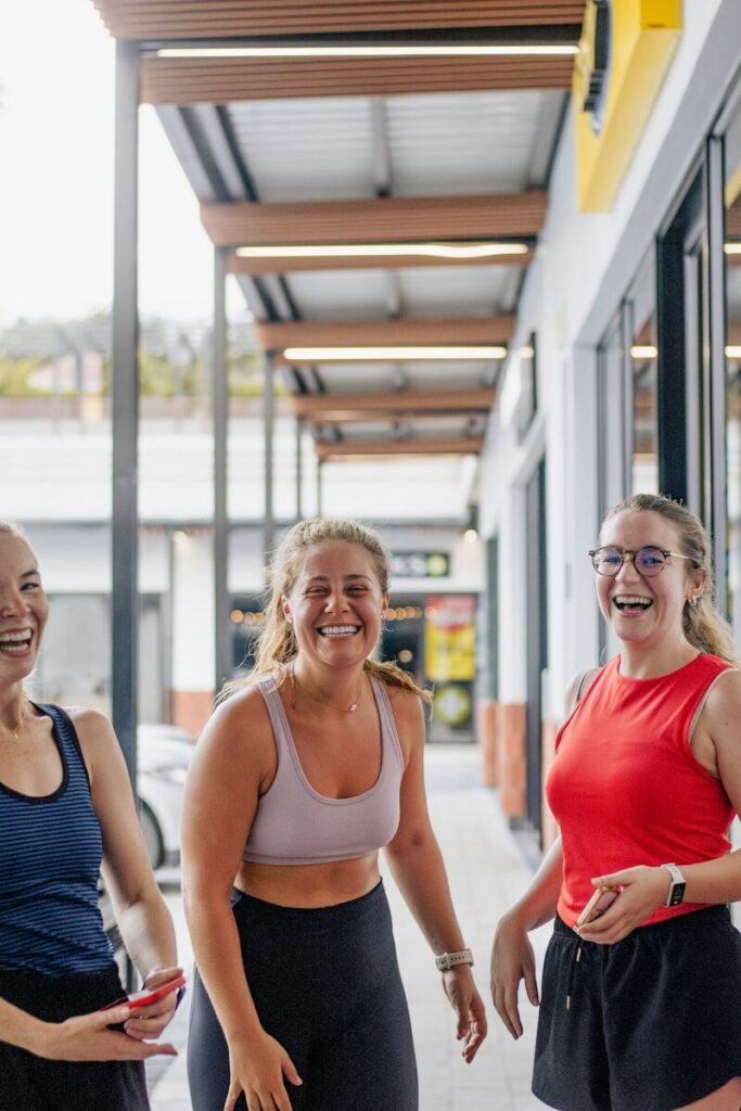 Three women laughing outdoors in activewear