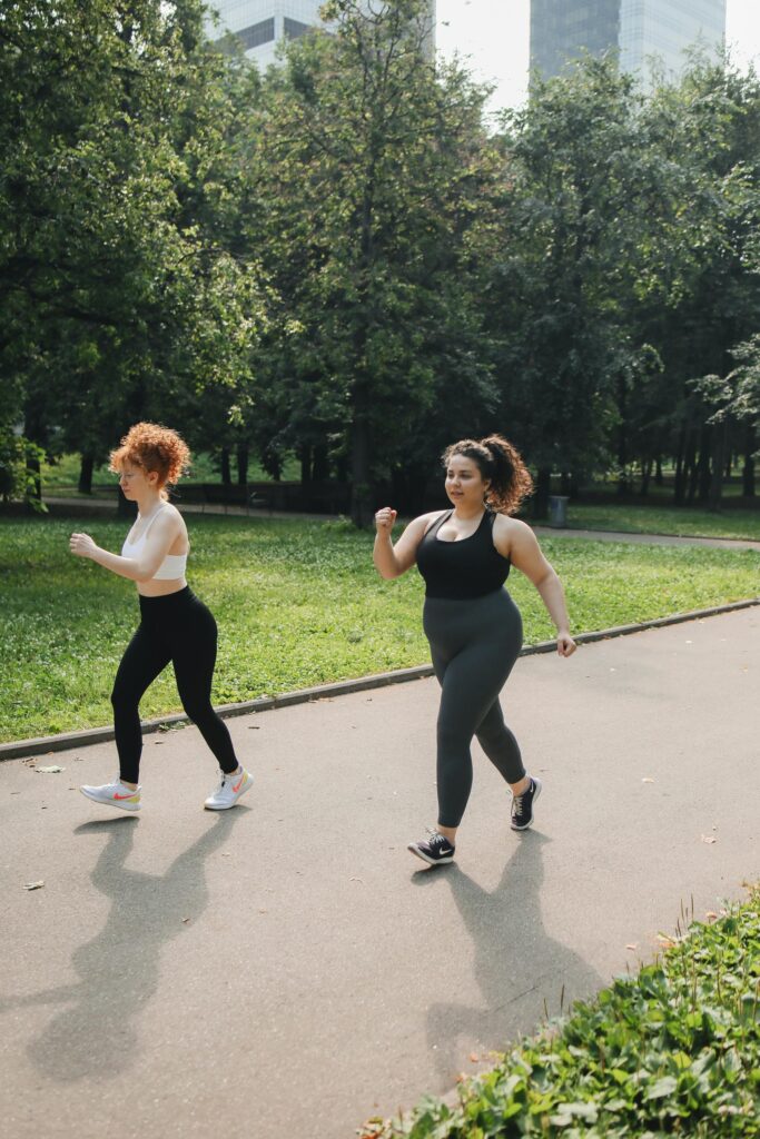 Two women power walking on a park path, enjoying outdoor fitness.
