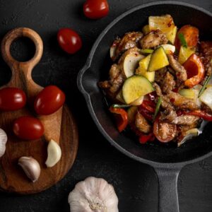 a pan filled with meat and vegetables next to garlic